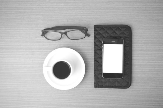 coffee,phone,eyeglasses and wallet on wood table background black and white color
