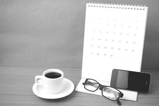 coffee,phone,eyeglasses and calendar on wood table background black and white color