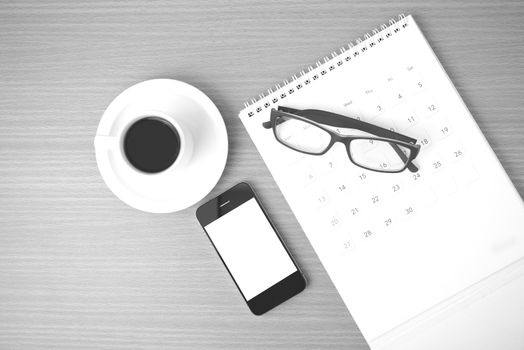 coffee,phone,eyeglasses and calendar on wood table background black and white color