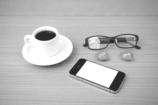 coffee,phone,eyeglasses and heart on wood table background black and white color