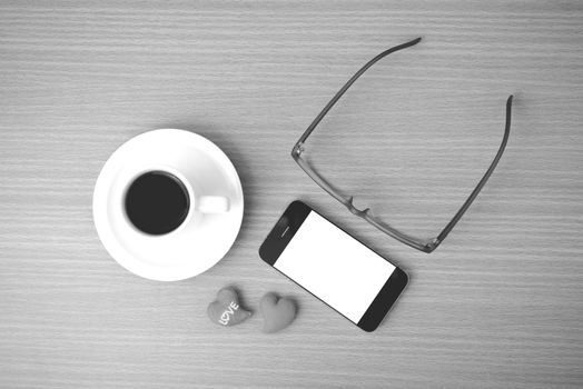 coffee,phone,eyeglasses and heart on wood table background black and white color