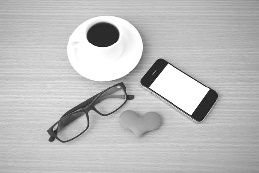 coffee,phone,eyeglasses and heart on wood table background black and white color
