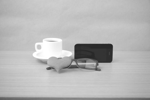 coffee,phone,eyeglasses and heart on wood table background black and white color