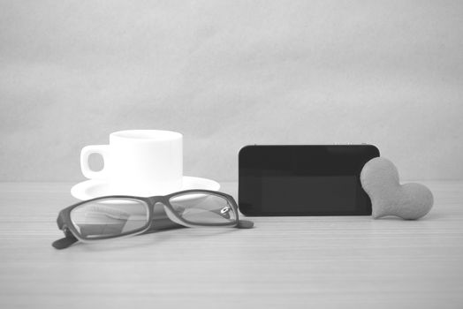 coffee,phone,eyeglasses and heart on wood table background black and white color