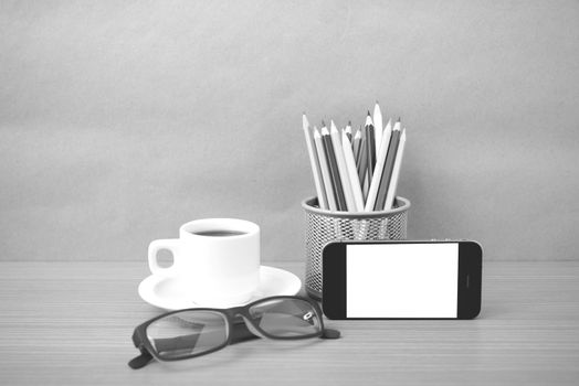 coffee,phone,eyeglasses and pencil on wood table background black and white color