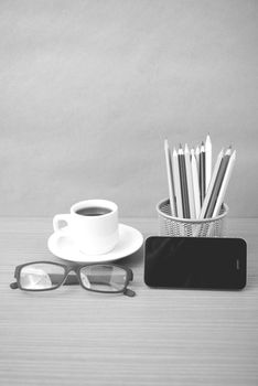 coffee,phone,eyeglasses and pencil on wood table background black and white color