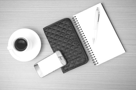 coffee,phone,notepad and wallet on wood table background black and white color