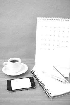 coffee,phone,notepad and calendar on wood table background black and white color