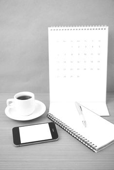 coffee,phone,notepad and calendar on wood table background black and white color