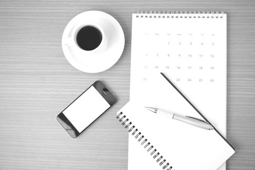 coffee,phone,notepad and calendar on wood table background black and white color