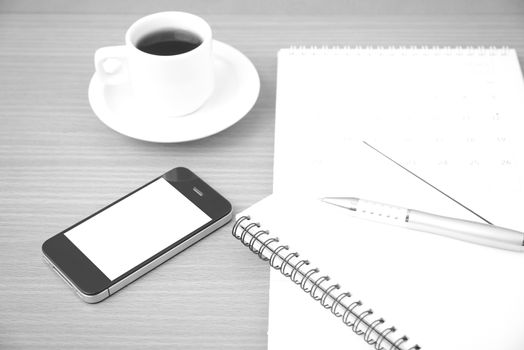 coffee,phone,notepad and calendar on wood table background black and white color