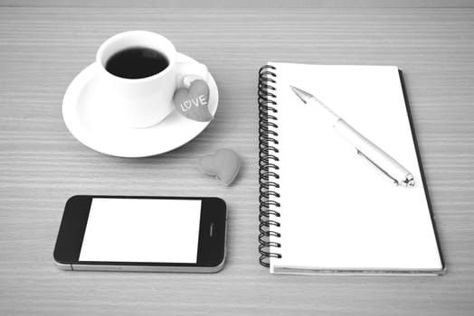 coffee,phone,notepad and heart on wood table background black  and white color