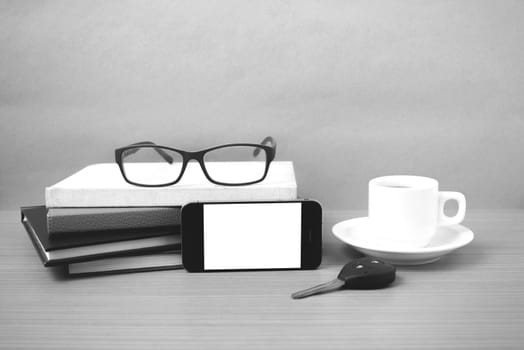 coffee,phone,car key,eyeglasses and stack of book on wood table background  black  and white color