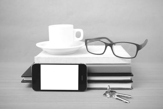 coffee,phone,key,eyeglasses and stack of book on wood table background black  and white color