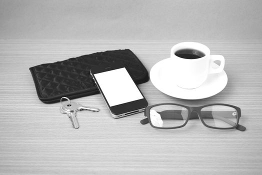 coffee,phone,key,eyeglasses and wallet on wood table background black  and white color