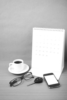 coffee,phone,car key,eyeglasses and calendar on wood table background black  and white color