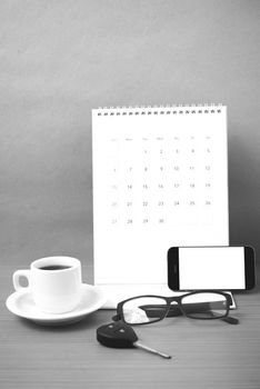 coffee,phone,car key,eyeglasses and calendar on wood table background black  and white color