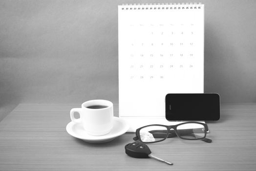 coffee,phone,car key,eyeglasses and calendar on wood table background black  and white color