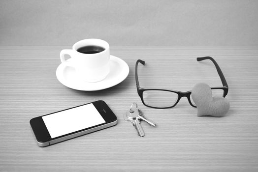 coffee,phone,eyeglasses,key and heart on wood table background black  and white color
