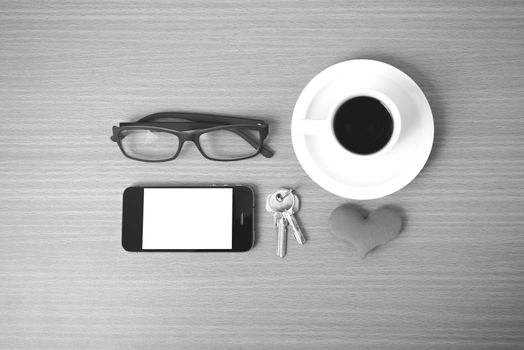 coffee,phone,eyeglasses,key and heart on wood table background black  and white color