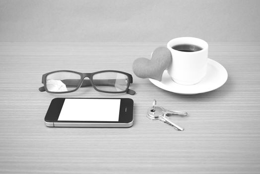 coffee,phone,eyeglasses,key and heart on wood table background black  and white color
