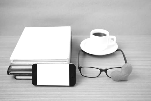 coffee,phone,eyeglasses,stack of book and heart on wood table background black  and white color