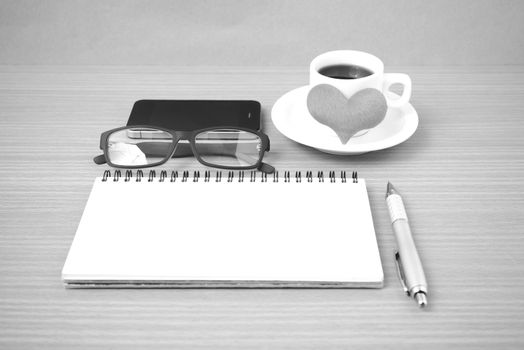 coffee,phone,eyeglasses,notepad and heart on wood table background black  and white color