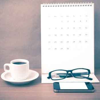 coffee,phone,eyeglasses and calendar on wood table background vintage style