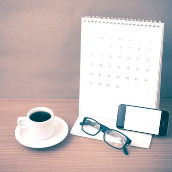 coffee,phone,eyeglasses and calendar on wood table background vintage style