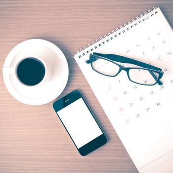 coffee,phone,eyeglasses and calendar on wood table background vintage style