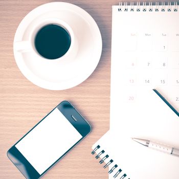 coffee,phone,notepad and calendar on wood table background vintage style