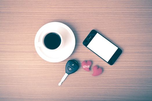 coffee phone car key and heart on wood table background vintage style