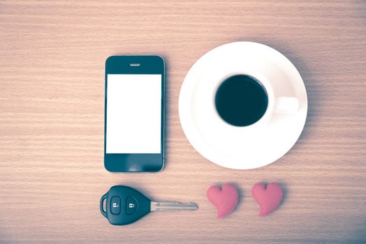 coffee phone car key and heart on wood table background vintage style