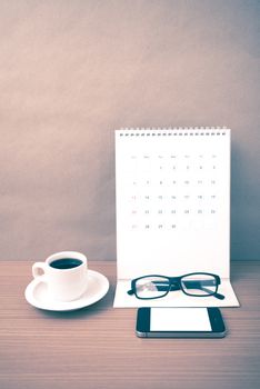 coffee,phone,eyeglasses and calendar on wood table background vintage style