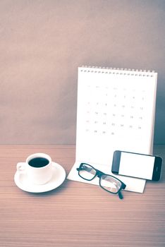 coffee,phone,eyeglasses and calendar on wood table background vintage style