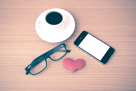coffee,phone,eyeglasses and heart on wood table background vintage style
