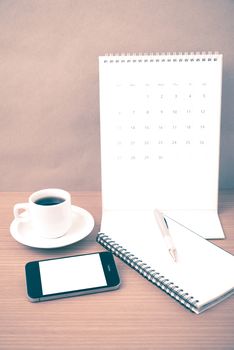 coffee,phone,notepad and calendar on wood table background vintage style