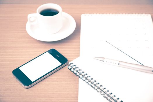 coffee,phone,notepad and calendar on wood table background vintage style