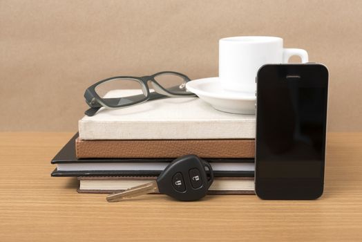 coffee,phone,car key,eyeglasses and stack of book on wood table background