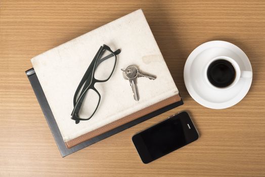 coffee,phone,key,eyeglasses and stack of book on wood table background