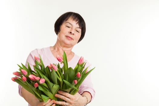the beautiful mature woman admires to a bouquet of tulips