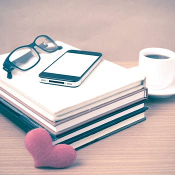 coffee,phone,eyeglasses,stack of book and heart on wood table background vintage style