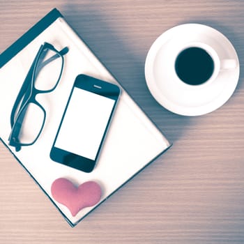 coffee,phone,eyeglasses,stack of book and heart on wood table background vintage style