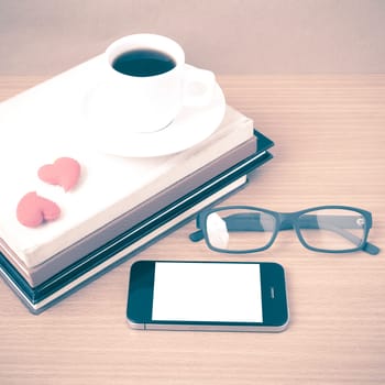 coffee,phone,eyeglasses,stack of book and heart on wood table background vintage style
