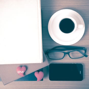 coffee,phone,eyeglasses,stack of book and heart on wood table background vintage style