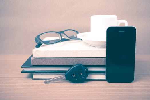 coffee,phone,car key,eyeglasses and stack of book on wood table background vintage style