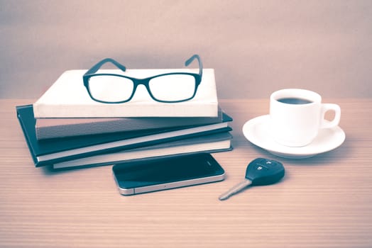 coffee,phone,car key,eyeglasses and stack of book on wood table background vintage style
