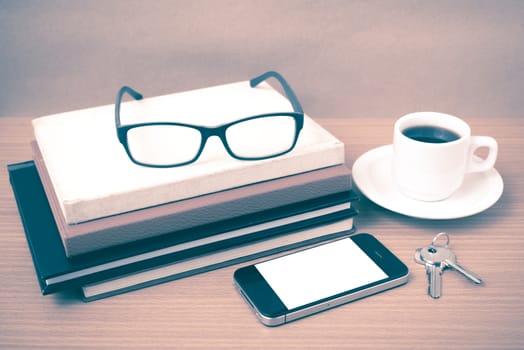 coffee,phone,key,eyeglasses and stack of book on wood table background vintage style