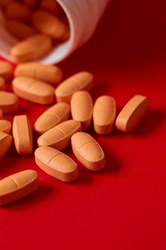 Pills spilling out of pill bottle on red. Top view with copy space. Medicine concept. Shallow dof