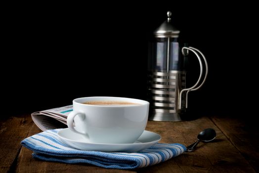 A cup of coffee with cream photographed under artistic lighting.